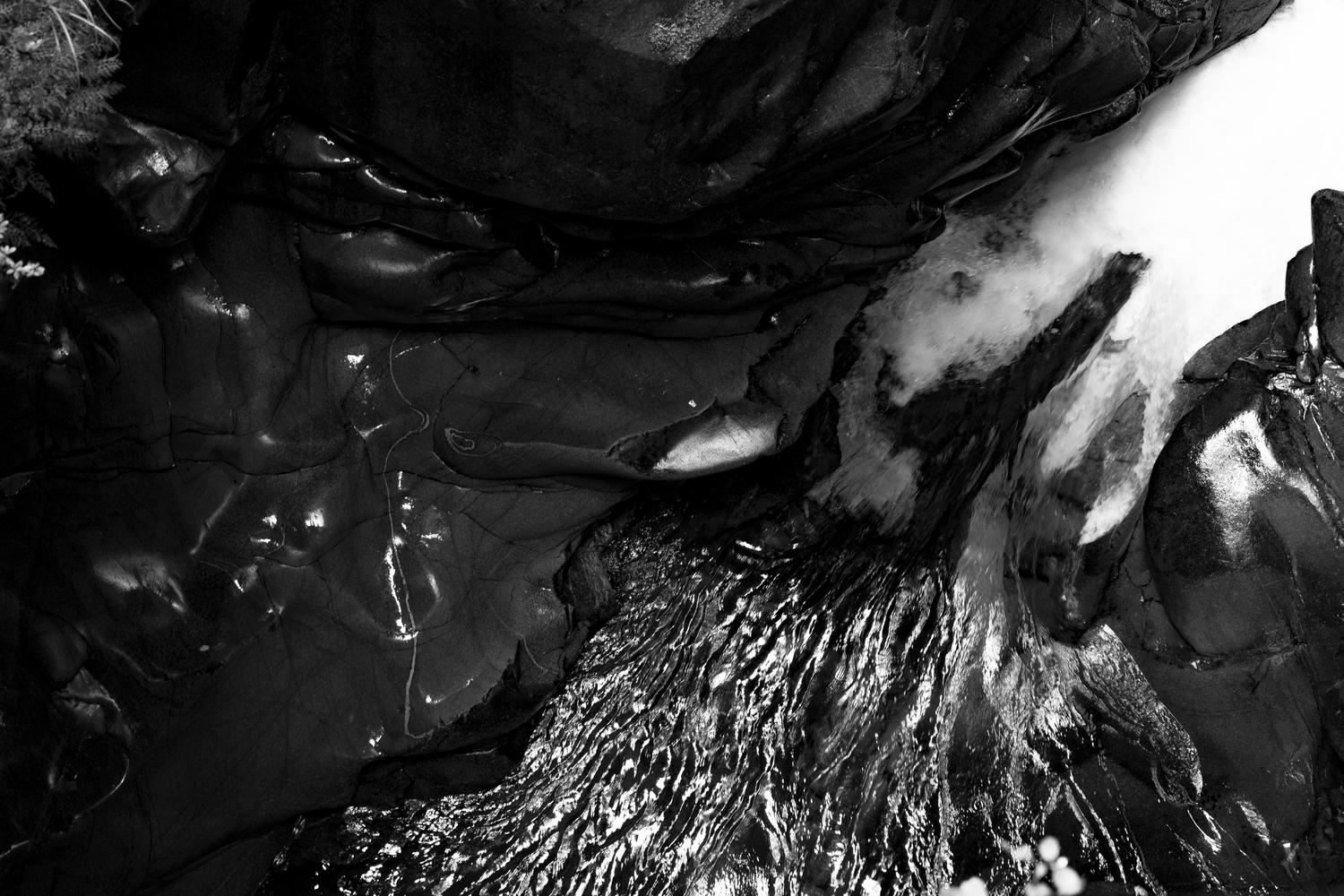 b&w photo showing folding shapes of fabric or lava on dark background